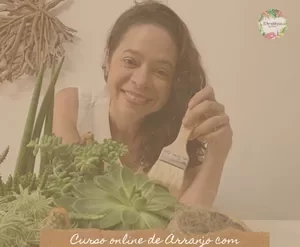 Mulher sorrindo montando arranjo de suculentas em vaso decorativo, vista de cima, com ferramentas de jardinagem ao lado.