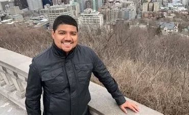 Homem sorrindo segurando um cartão de crédito com um fundo de milhas aéreas digitais