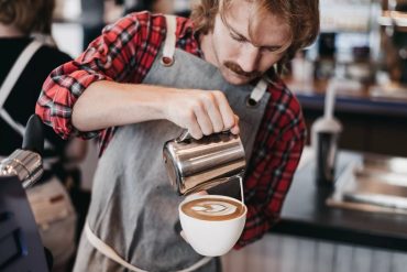 Barista preparando café especial com latte art detalhada em xícara