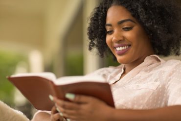 Mulher cristã sorrindo com um livro sobre sexualidade e fé