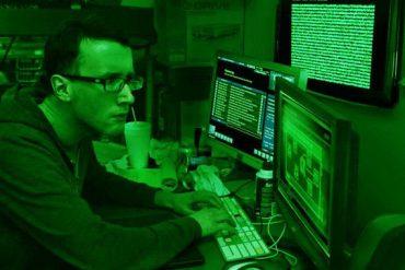 Homem programando em computador com código de segurança cibernética e hacker na tela, conceito de web hacking prático.