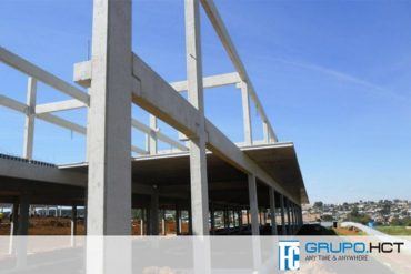 Homem trabalhando em projeto de concreto pré-moldado com plantas e computador